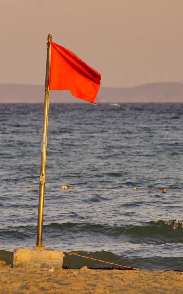 Red warning flag on a beach as a symbol for an important warning